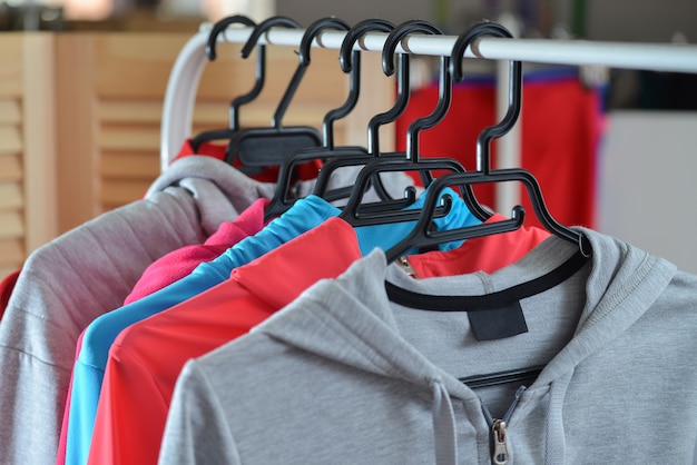 Coloridas camisas deportivas y chaquetas colgadas en el perchero en una tienda de moda