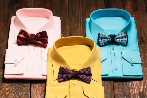 Coloridas camisas masculinas con pajarita en el escritorio de madera