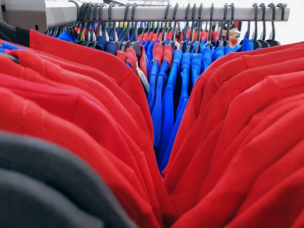 Foto coloridas camisetas y polos que cuelgan en los estantes con enfoque selectivo