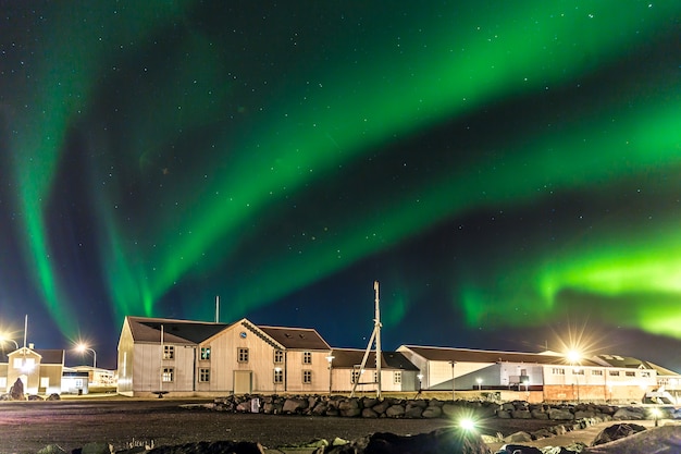 Foto coloridas luces del norte (aurora boreal) con un almacén en primer plano en islandia