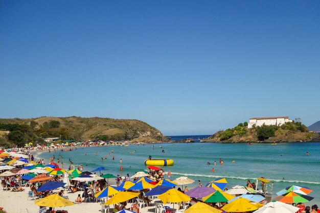 coloridas sombrillas y turistas llenan la línea de arena en Praia do Forte en Cabo Frio, Río de Janeiro