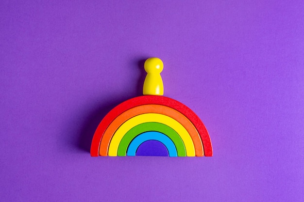 Colorido arco iris de figura humana de madera waldorf en una pedagogía de enseñanza montessori sobre fondo púrpura