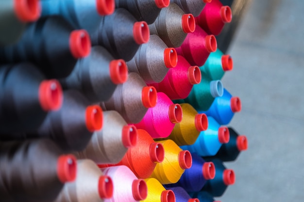 Colorido carrete de hilo de bordar en la industria de la confección, fila de rollos de hilo multicolor, venta de material de costura en el mercado