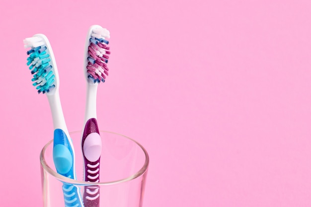Colorido cepillo de dientes en un vaso. Concepto de higiene bucal. Fondo rosa
