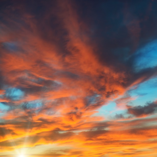 Colorido cielo dramático naranja y azul con nubes y sol brillante