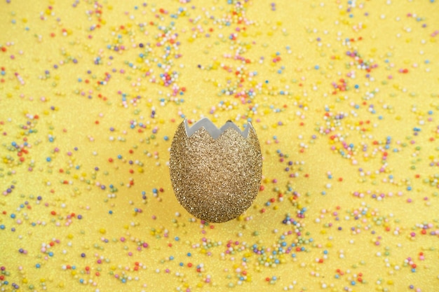 Foto colorido confeti disperso y cáscara de huevo dorada sobre fondo amarillo confeti festivo