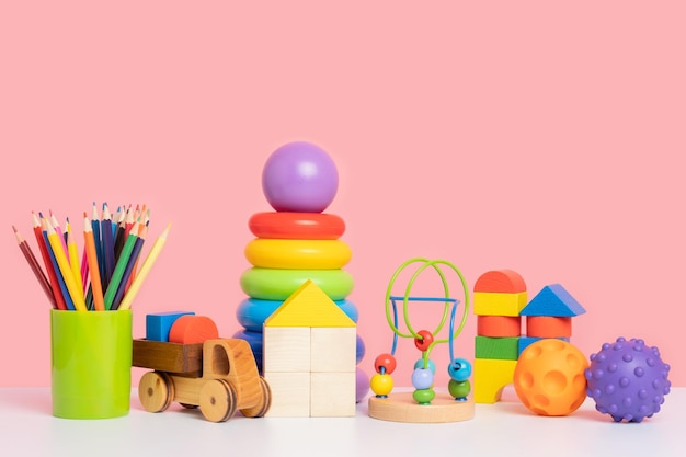 Un colorido conjunto de juguetes educativos para niños en edad preescolar Juguetes de madera y plástico sobre un fondo rosa Copiar espacio