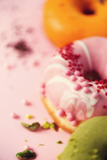 Colorido donuts con glaseado en rosa pastel. Dulce naranja, verde, rosquillas rosadas con pistacho, chocolate.