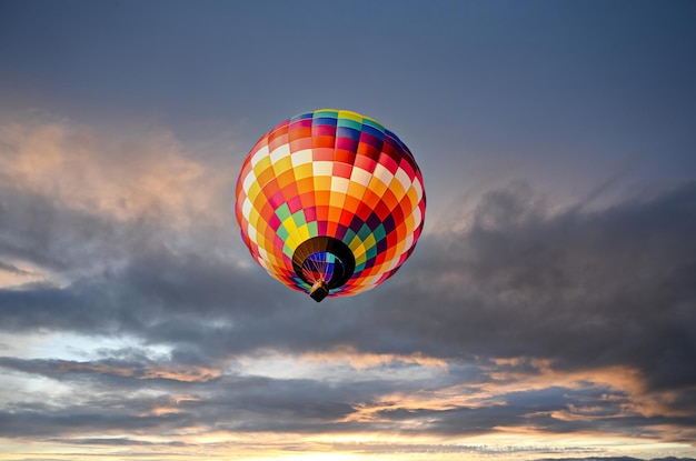 Colorido globo aerostático volando sobre el cielo al atardecer.