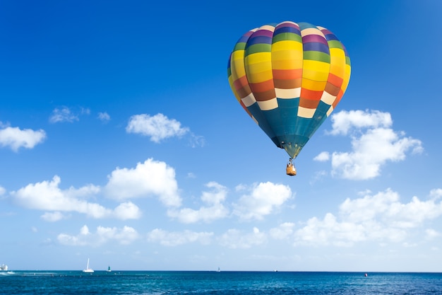 Colorido globo de aire caliente sobre el océano con cielo azul