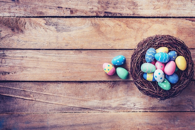 Colorido huevo de Pascua en el nido sobre fondo de madera con espacio