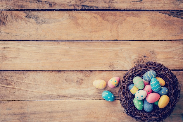 Colorido huevo de Pascua en el nido sobre fondo de madera con espacio