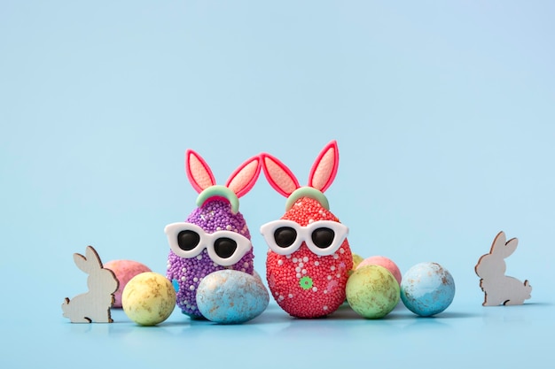 Foto colorido huevo de pascua con orejas de conejo y gafas de sol sobre un fondo azul plantilla de maqueta de banner de venta con espacio de copia