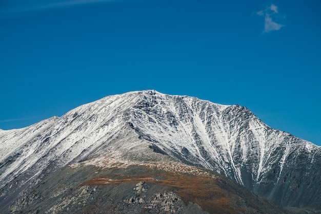 Colorido paisaje alpino con gran montaña en colores otoñales con nieve en el pico bajo el sol en el cielo azul. Pintoresco paisaje otoñal con la cima de una montaña cubierta de nieve. Impresionante vista al vívido pico de la montaña.