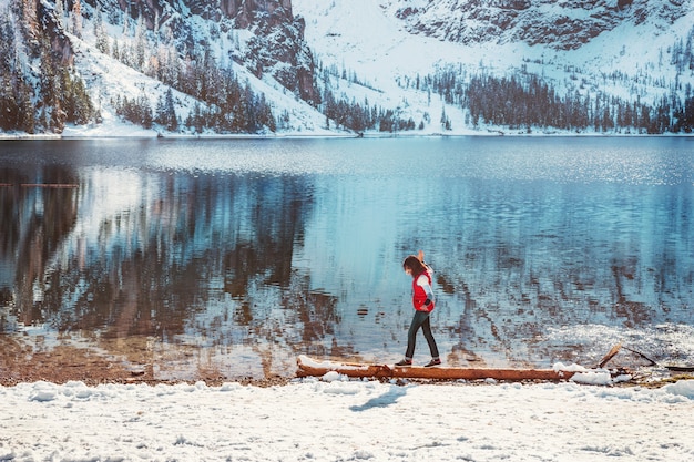 Colorido paisaje de invierno con una mujer caminando por el lago de montaña Braies, Dolomitas.