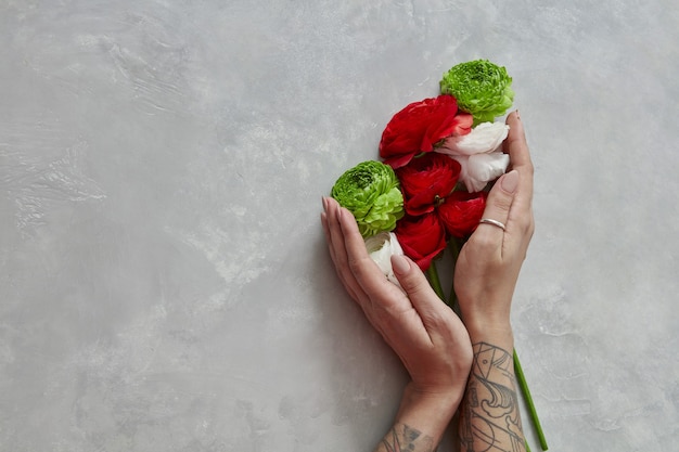 un colorido ramo de flores diferentes sostiene a una niña sobre un fondo de hormigón gris. Día de San Valentín o Día de la Madre