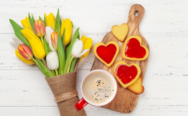 Colorido ramo de flores de tulipán galletas y café en forma de corazón