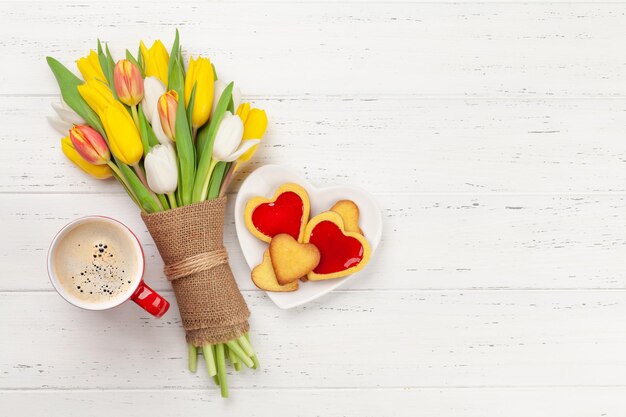 Colorido ramo de flores de tulipán galletas y café en forma de corazón