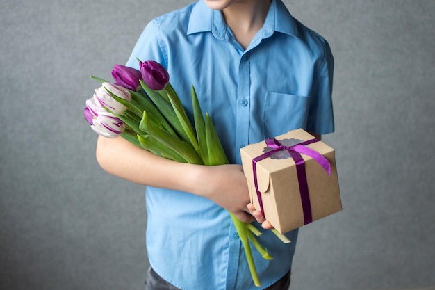 Colorido ramo de tulipanes con una caja de regalo en manos de un niño