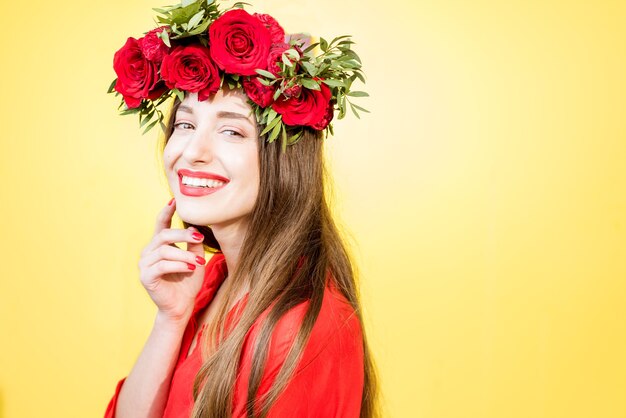 Colorido retrato de una bella mujer en vestido rojo con corona de rosas rojas sobre fondo amarillo