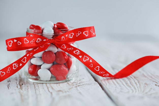 Colorido tarro de caramelo decorado con un lazo rojo con corazones.