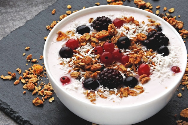 Colorido tazón de desayuno saludable con bayas, yogur y granola. Vista superior.