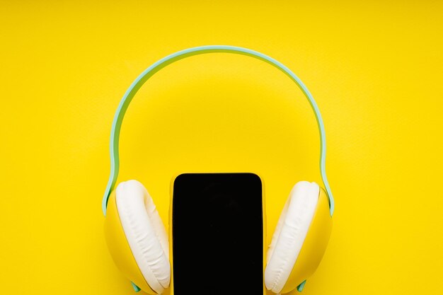 Coloridos auriculares inalámbricos con smartphone aislado sobre fondo amarillo