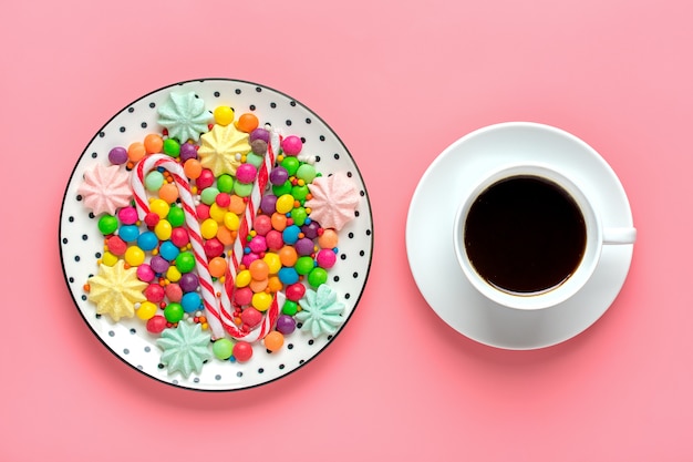 Coloridos dulces en un plato y una taza de café