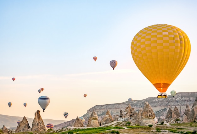 Coloridos globos de aire caliente volando sobre el paisaje rocoso en Capadocia Turquía