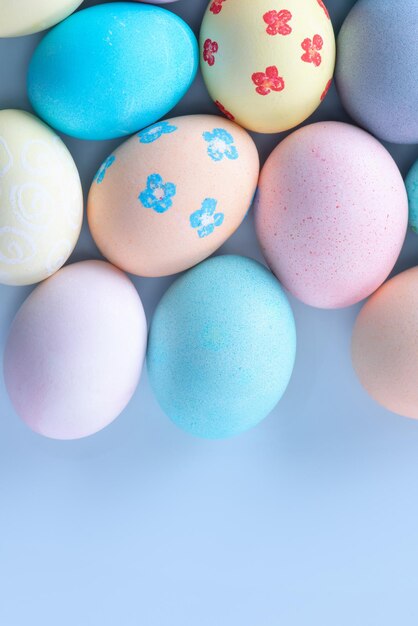 Coloridos huevos de caza de Pascua teñidos con agua coloreada con un hermoso patrón en el concepto de diseño de fondo azul pastel del espacio de copia de la vista superior de vacaciones