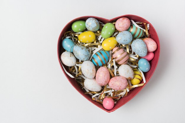 Coloridos huevos de Pascua en caja en forma de corazón en blanco