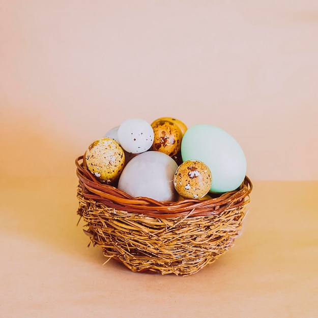 Coloridos huevos de Pascua en una canasta de mimbre sobre fondo de luz suave.