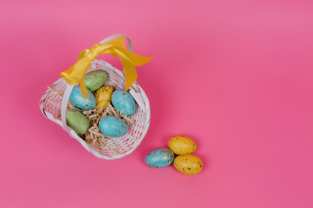 Coloridos huevos de Pascua en una canasta sobre un fondo rosa