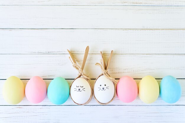 Coloridos huevos de pascua con caras pintadas y orejas de conejo en fila en blanco