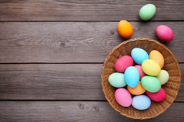 Coloridos huevos de pascua en cesta en madera gris