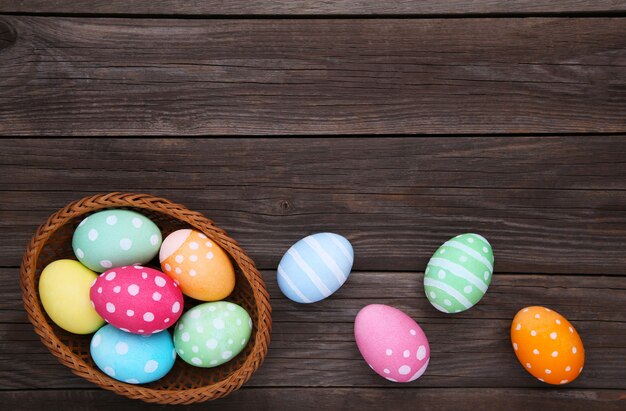 Coloridos huevos de pascua en cesta en madera gris