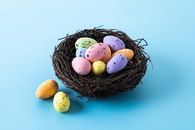 Coloridos huevos de Pascua dentro de un nido sobre fondo azul.