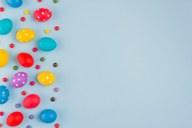 Foto coloridos huevos de pascua con dulces en la mesa