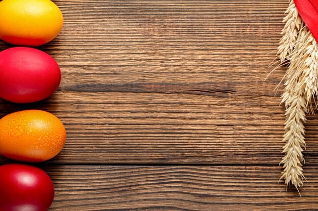 Coloridos huevos de Pascua con espigas de trigo sobre fondo de madera marrón