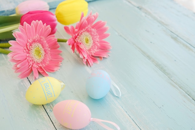 Coloridos huevos de Pascua con flores en el fondo de tablas de madera rústica