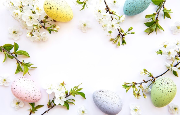 Coloridos huevos de Pascua con flores de primavera en flor aislado sobre superficie blanca