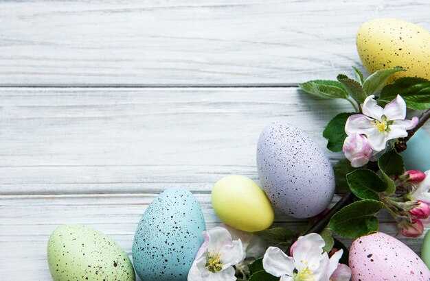 Coloridos huevos de Pascua con flores de primavera sobre mesa de madera.