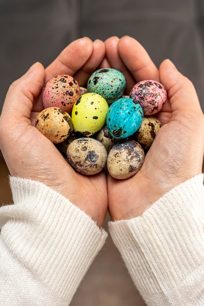 Coloridos huevos de pascua en manos de mujeres huevos de codorniz