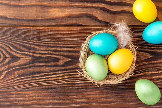 Coloridos huevos de Pascua en el nido y cerca de madera rural