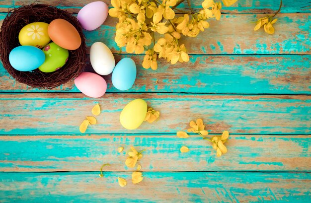 Coloridos huevos de Pascua en el nido con flores. Vacaciones en temporada de primavera