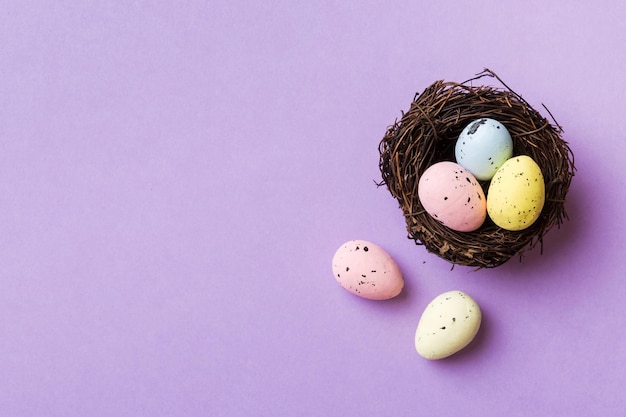 Coloridos huevos de pascua en el nido en el fondo de la mesa con vista superior del espacio de copia