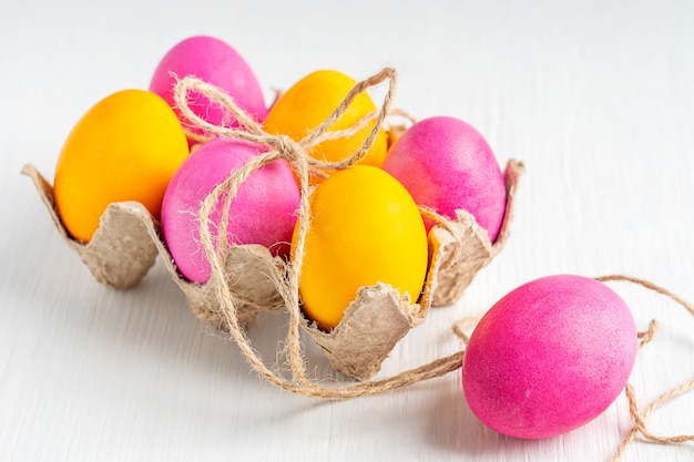 Coloridos huevos de pascua en un nido sobre una mesa de madera blanca