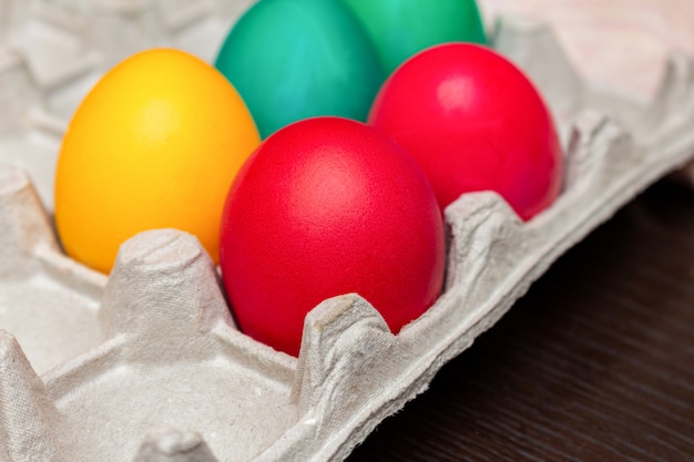 Coloridos huevos de Pascua pintados en una caja de papel de cerca