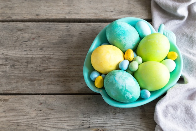 Coloridos huevos de pascua en una placa de color turquesa sobre un fondo de madera cutre