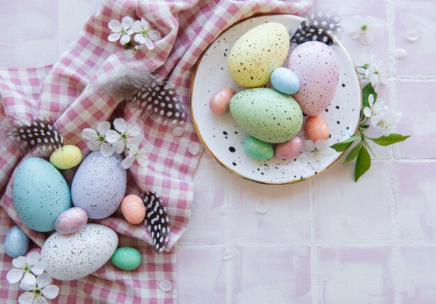 Coloridos huevos de Pascua en la placa en la vista superior de fondo de azulejo rosa